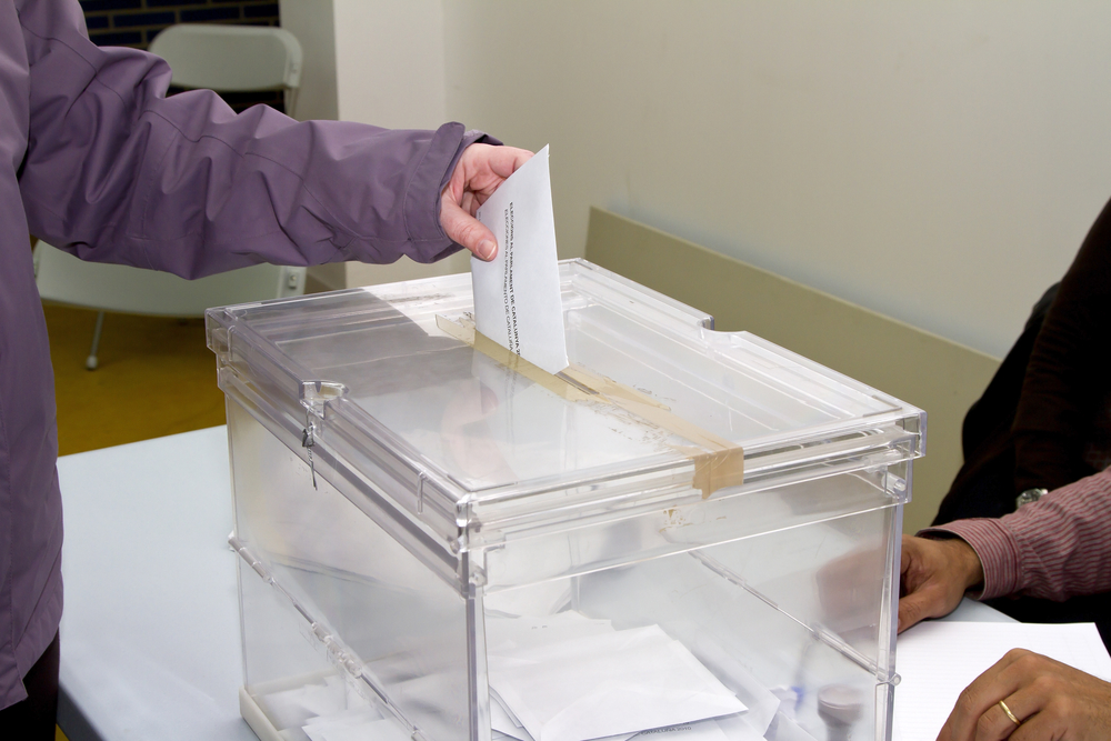 Detalle de persona introduciendo su voto en una urna. Elecciones